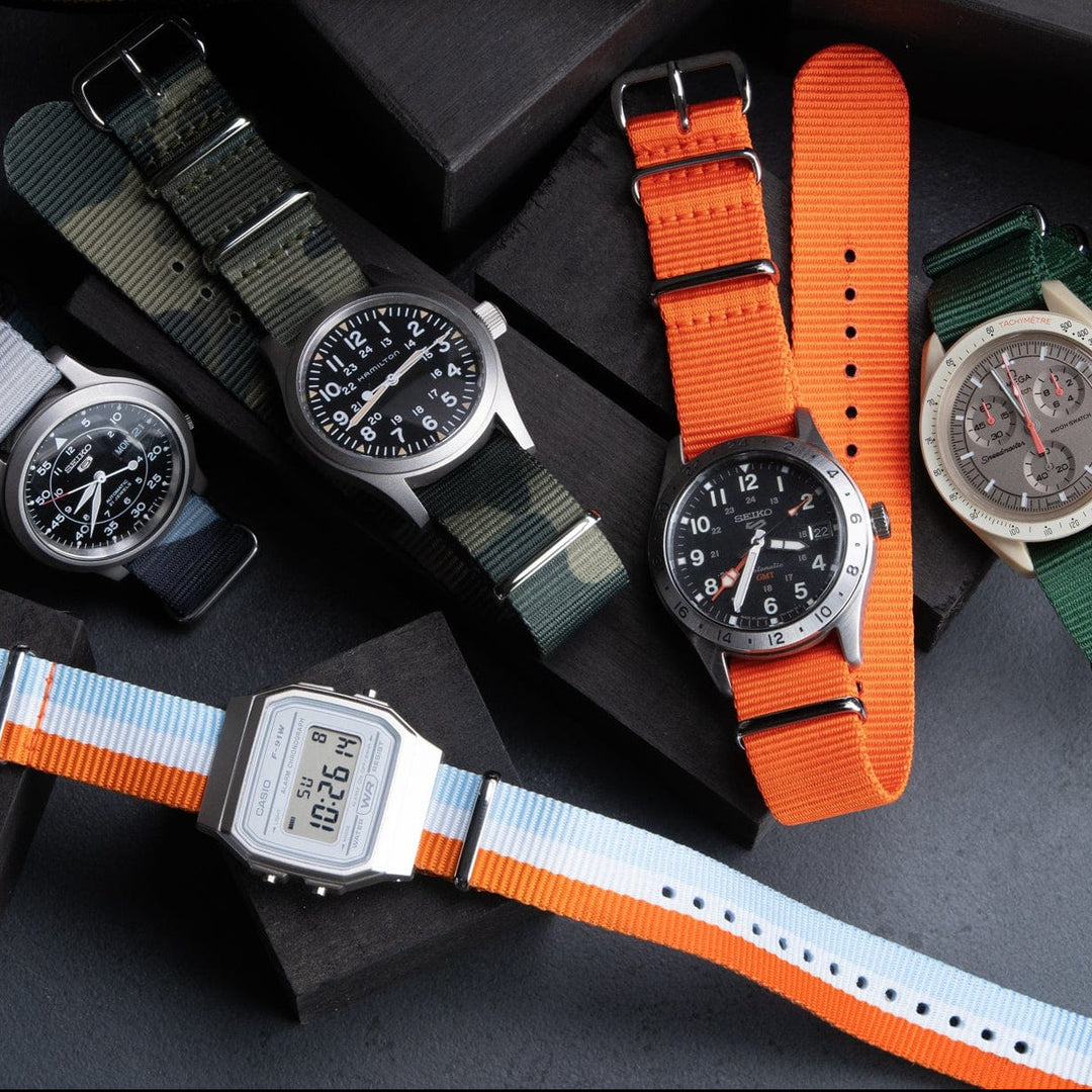 Assortment of military style watch straps in multiple colors including orange, green, navy, and striped styles